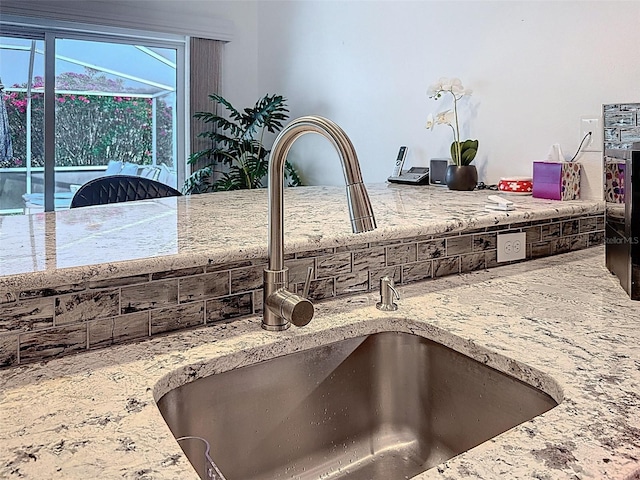 interior details featuring light stone counters and a sink