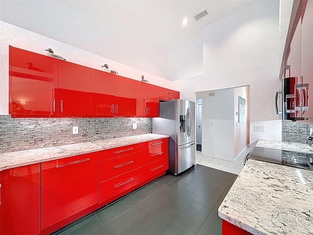 kitchen with electric range, stainless steel fridge with ice dispenser, visible vents, red cabinetry, and backsplash