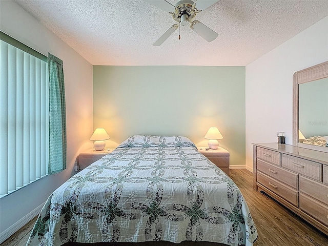 bedroom with a ceiling fan, baseboards, a textured ceiling, and wood finished floors
