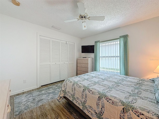 bedroom featuring wood finished floors, a closet, a textured ceiling, visible vents, and ceiling fan