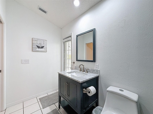 half bathroom with a textured ceiling, visible vents, tile patterned flooring, vanity, and vaulted ceiling
