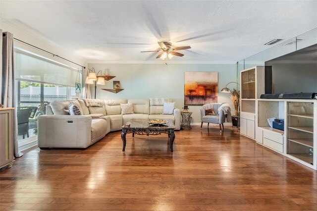 living area featuring visible vents, a ceiling fan, wood-type flooring, and ornamental molding