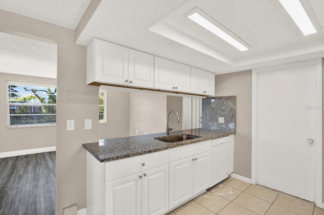 kitchen featuring a sink, baseboards, white cabinetry, and dishwasher
