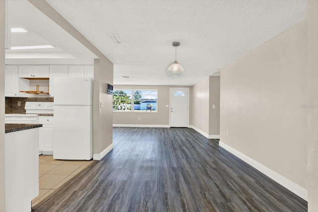 interior space with baseboards, a textured ceiling, and wood finished floors
