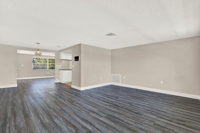 unfurnished living room with a textured ceiling, visible vents, baseboards, and dark wood-type flooring