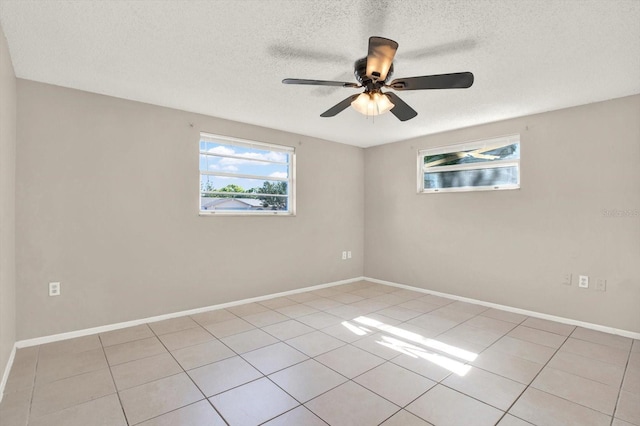 spare room featuring light tile patterned floors, baseboards, ceiling fan, and a textured ceiling