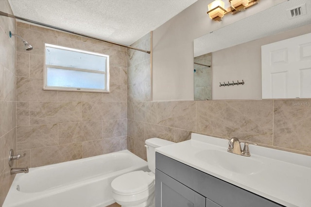 bathroom featuring visible vents, toilet, bathing tub / shower combination, tile walls, and a textured ceiling