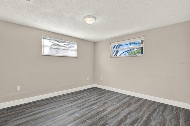 empty room featuring baseboards, dark wood-style floors, and a textured ceiling