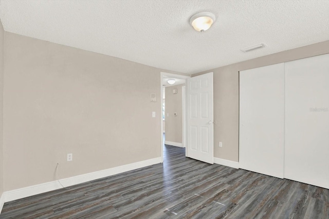 unfurnished bedroom with baseboards, a textured ceiling, wood finished floors, and a closet