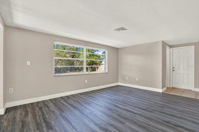 spare room featuring visible vents, a textured ceiling, and wood finished floors