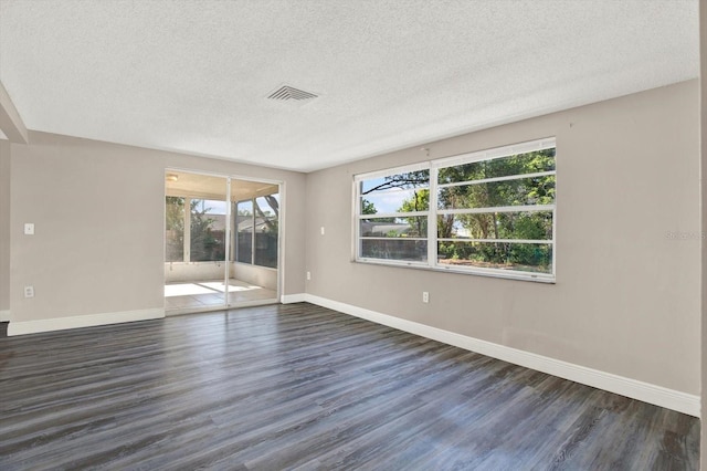 spare room featuring baseboards, a textured ceiling, visible vents, and dark wood finished floors