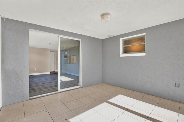 spare room with tile patterned flooring, a textured ceiling, and a textured wall