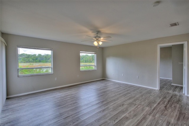 empty room featuring baseboards, ceiling fan, wood finished floors, and visible vents