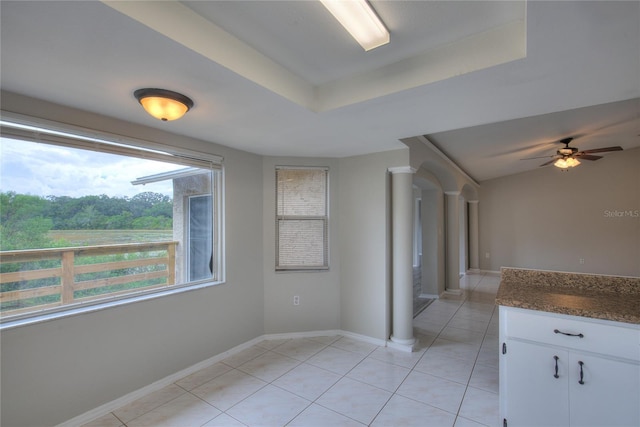 interior space featuring baseboards, a ceiling fan, a raised ceiling, and light tile patterned floors
