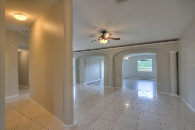 unfurnished room featuring baseboards, arched walkways, ceiling fan, and light tile patterned floors