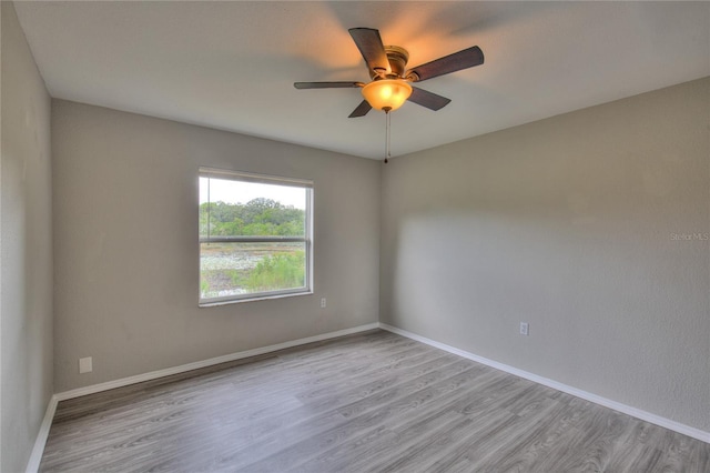 unfurnished room with a ceiling fan, baseboards, and wood finished floors