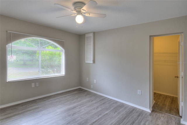 empty room featuring a ceiling fan, baseboards, and light wood finished floors