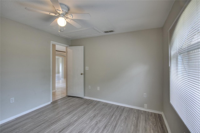 spare room with a ceiling fan, baseboards, visible vents, and wood finished floors