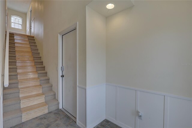 stairs with a decorative wall and a wainscoted wall