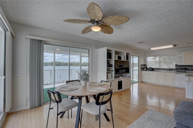 dining space with a wainscoted wall, a textured ceiling, and a wealth of natural light