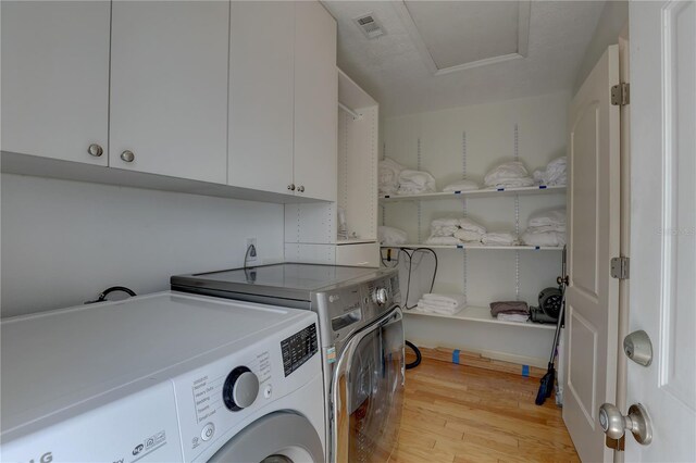 laundry area featuring cabinet space, independent washer and dryer, light wood-style flooring, attic access, and visible vents