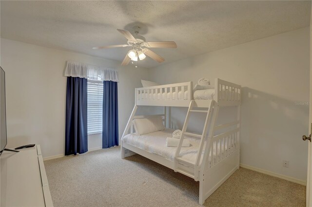 bedroom featuring baseboards, a textured ceiling, carpet, and ceiling fan
