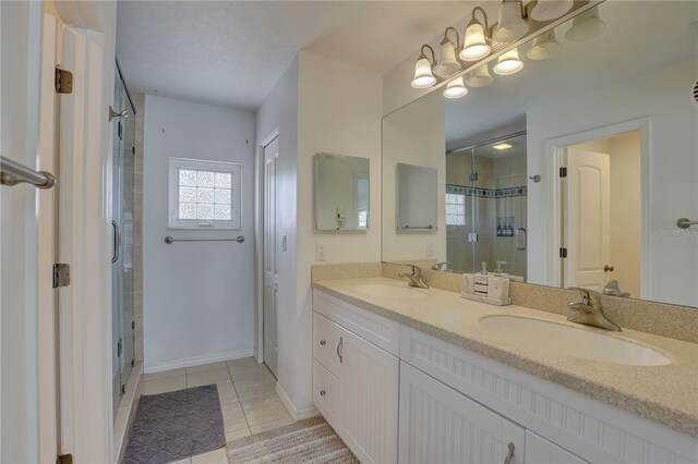 bathroom with a sink, tile patterned flooring, a shower stall, and double vanity