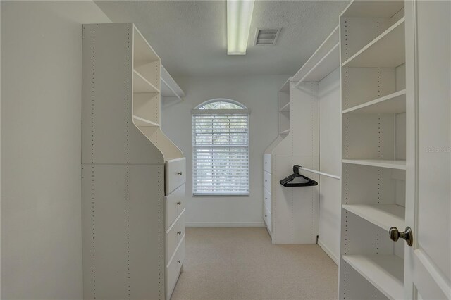 walk in closet with light colored carpet and visible vents