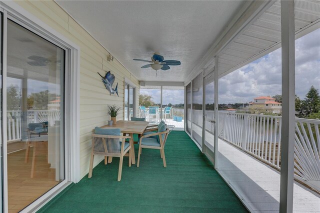 sunroom with outdoor dining area, a water view, and ceiling fan
