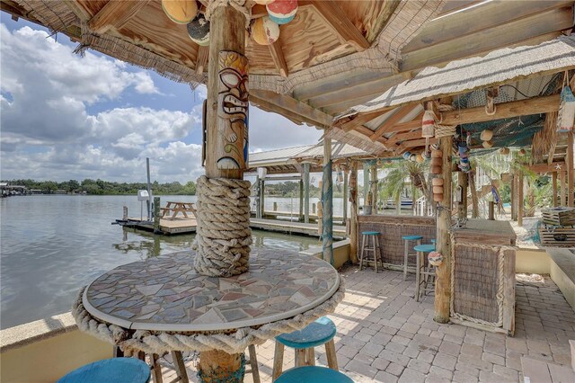 view of patio / terrace featuring outdoor dry bar, a boat dock, and a water view