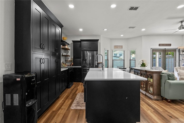 kitchen featuring dark cabinets, open floor plan, visible vents, and light wood-style floors