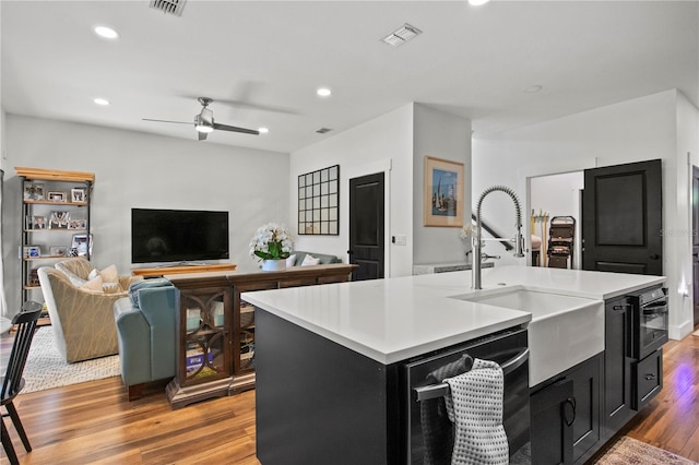 kitchen featuring dark cabinets, a sink, light wood-style floors, and light countertops