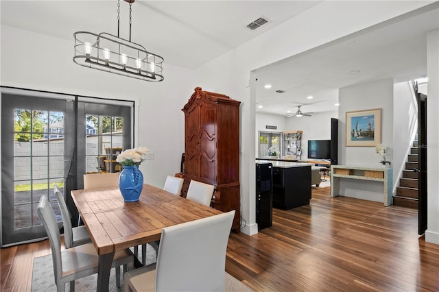 dining space featuring dark wood finished floors, ceiling fan with notable chandelier, recessed lighting, visible vents, and stairway