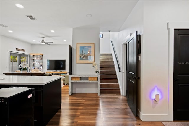 kitchen featuring ceiling fan, visible vents, wood finished floors, light countertops, and dark cabinetry