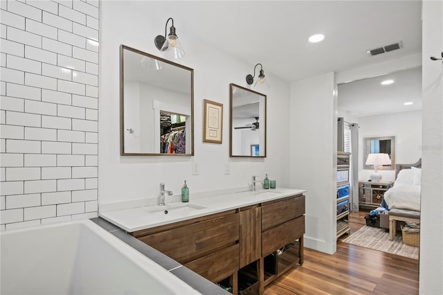 full bath with visible vents, double vanity, wood finished floors, ensuite bathroom, and a sink