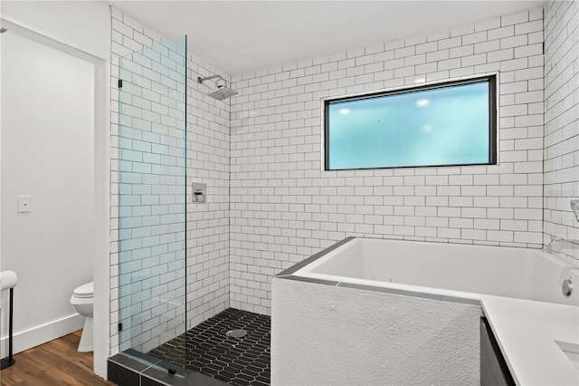 full bath with toilet, wood finished floors, a bath, and a stall shower