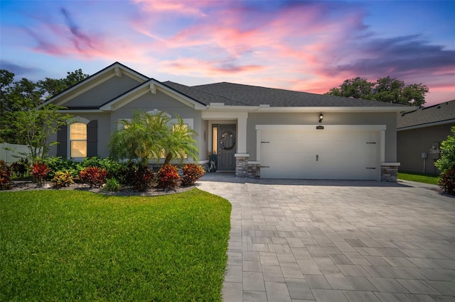 view of front of house with a garage, stucco siding, decorative driveway, and a lawn