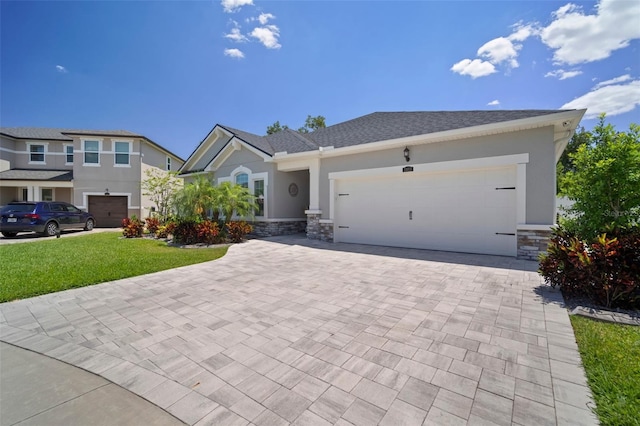 view of front of home featuring an attached garage, stone siding, stucco siding, a front lawn, and decorative driveway