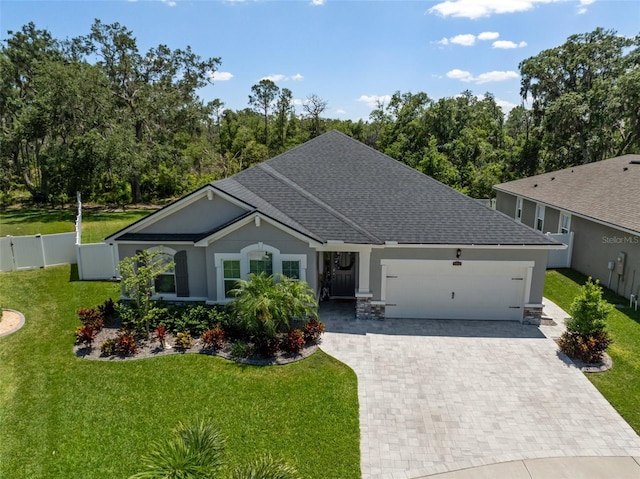ranch-style house with a garage, fence, a front lawn, decorative driveway, and roof with shingles