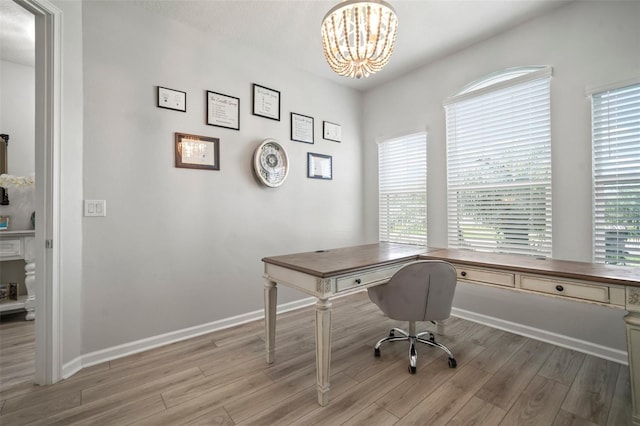 office area featuring baseboards, a notable chandelier, and light wood finished floors