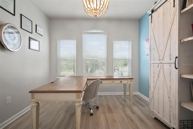office area with light wood-style floors, a barn door, baseboards, and a notable chandelier