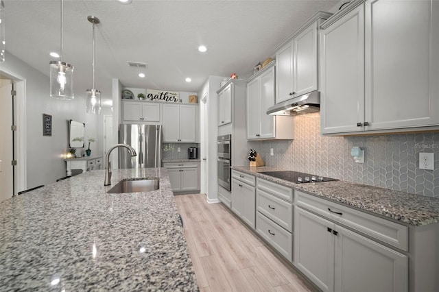 kitchen with under cabinet range hood, visible vents, a sink, backsplash, and stainless steel appliances
