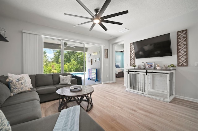 living area featuring baseboards, light wood finished floors, ceiling fan, and visible vents