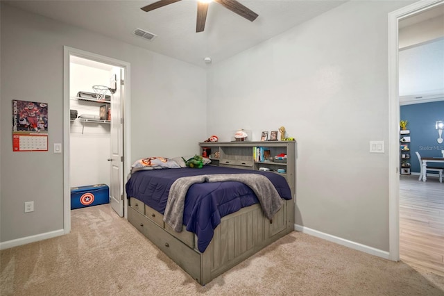 bedroom with carpet flooring, visible vents, baseboards, and a walk in closet