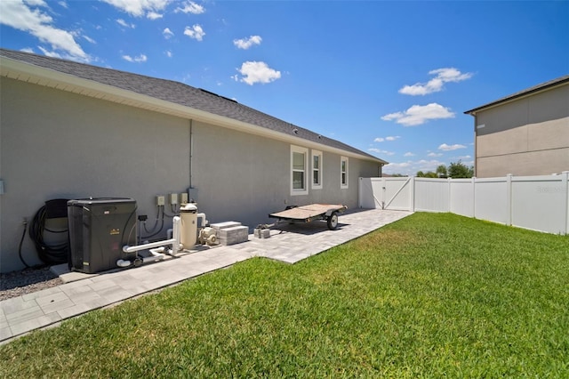 back of house featuring a gate, stucco siding, fence, a yard, and a patio area