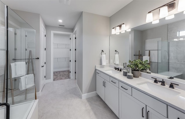 bathroom featuring a walk in closet, visible vents, a sink, and a shower with shower door