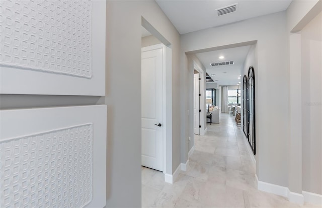hall featuring baseboards, recessed lighting, and visible vents