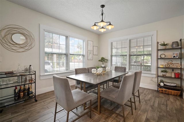 dining space with baseboards, plenty of natural light, dark wood finished floors, and a notable chandelier