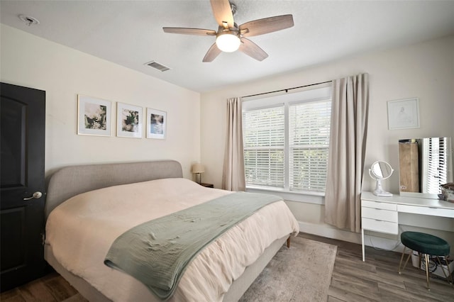 bedroom with baseboards, a ceiling fan, wood finished floors, and visible vents