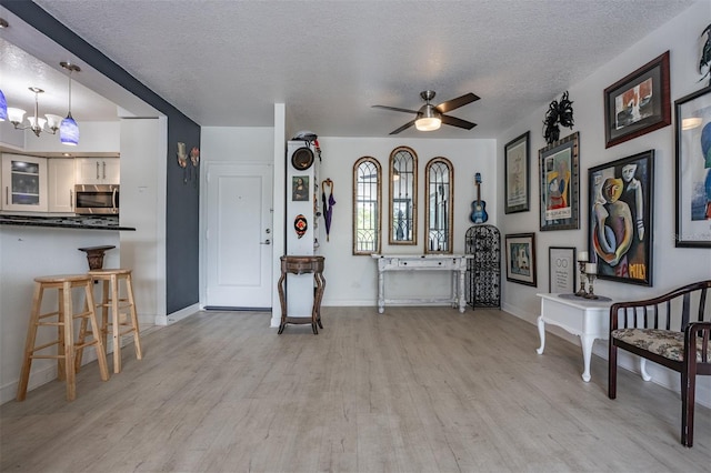 30 Turner St Unit 202, Clearwater, FL 33756 - foyer entrance featuring light wood finished floors, a textured ceiling, baseboards, a ceiling fan, and a chandelier
